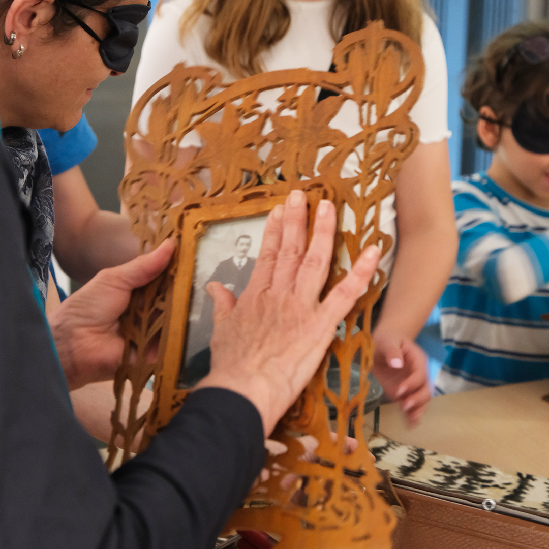 une personne aux yeux bandés examine un cadre photo en bois à l'aide de ses mains